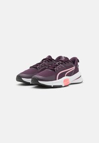 Zapatillas deportivas moradas con parte superior de malla, acentos en rosa contrastante, entresuela blanca y suela negra. Cuenta con cordones y cuello acolchado.