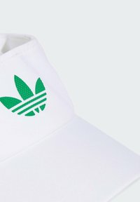 Fehér kalap széles karimával, zöld Adidas logóval, amely három csíkkal és levélmintával rendelkezik. Sima tapintású, minimalista dizájn.