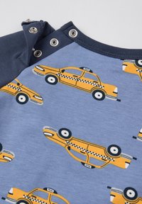 Lichtblauwe stof met gedrukte gele taxi's, met zwart-witte details op de wielen. Grijsblauwe mouwen met drukknopen bij de kraag.
