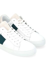 Sneakers bianchi con accenti in suede marrone, un pannello laterale verde, caratterizzati da un classico design con lacci e suola in gomma testurizzata.