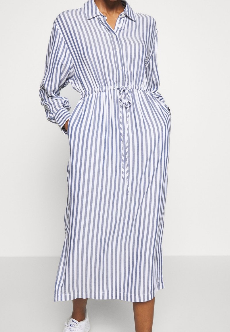Gestreiftes Hemdkleid in Blau und Weiß, mit langen Ärmeln, elastischem Bund mit Bindegürtel und Seitentaschen. Midi-Länge.