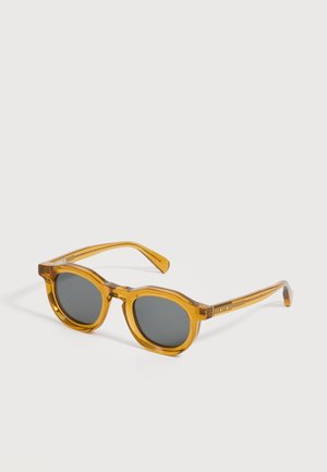 Runde Sonnenbrille mit bernsteinfarben transparenten Fassungen und dunkelgrauen Gläsern, gezeigt auf weißem Hintergrund.
