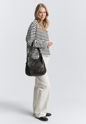 Borsa hobo in pelle nera con finitura texture, forma a arco, tracolla regolabile e dettagli di cucitura sottili, abbinata a una maglietta a maniche lunghe a righe.