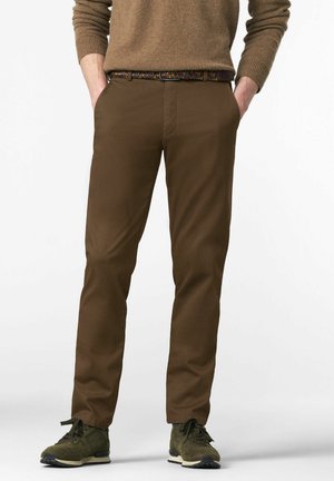 Chinos marron avec une finition texturée, dotés de poches latérales, accompagnés d'une ceinture tissée multicolore et de baskets vertes.