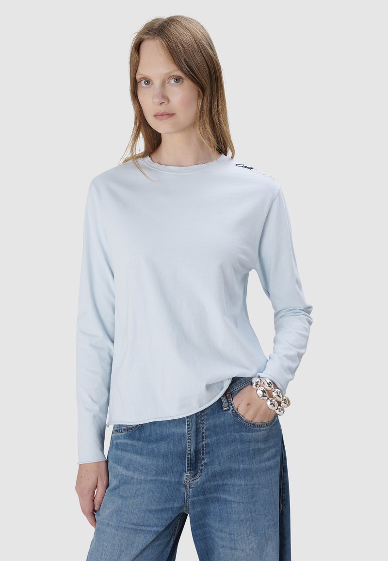 Hellblaues Langarmshirt aus weichem Stoff mit rundem Ausschnitt und dezentem Saumdetail. Mit subtiler Markenkennzeichnung auf der Schulter.