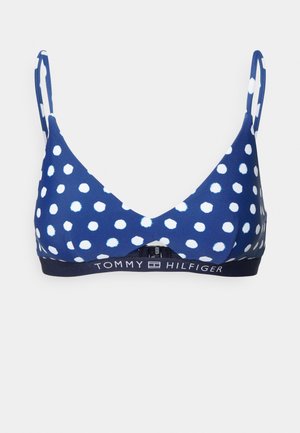 Bralette azul-marinho com bolinhas, feito de tecido elástico, com alças finas e uma faixa elástica com marca, apresentando bolinhas brancas por toda a parte.