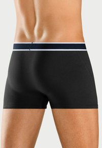 Svarta boxershorts med en åtsittande design och mjukt tyg. Har en marinblå midjeband med ett vitt streck, slät textur och minimal sömnad.