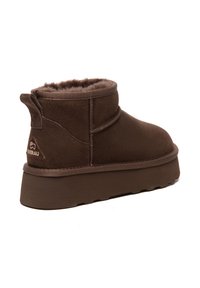 Braun schicke Stiefelette aus Wildleder mit weichem Fellfutter, flexibel Gummisohle und kleinem gesticktem Logo auf der Rückseite. Verfügt über eine Zuglasche für ein einfaches Anziehen.