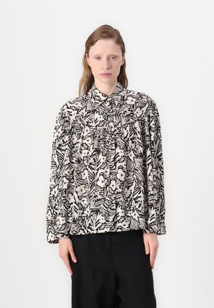 Svart-hvitt blomstermønstretebluse med lange ermer, rynkede detaljer foran og kragehals. Glatt tekstur.