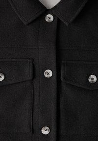 Veste en laine noire avec un col, deux poches à l'avant et des boutons argentés au motif croisé. Texture douce avec un design épuré.