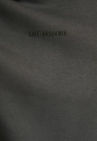Tessuto grigio scuro con una texture a coste, caratterizzato da testi neri in rilievo "LOT 33004/03" sulla superficie.