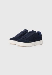 Tenisi din suede bleu marin cu vârful rotund, talpă din cauciuc alb texturat și șireturi în ton. Au logo-ul auriu "ARKK" pe lateral.