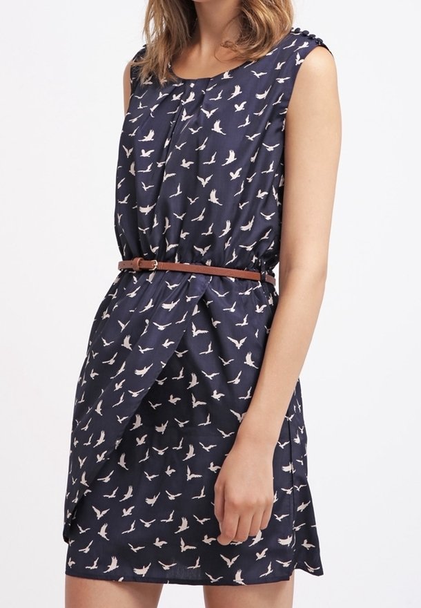 Laivastonsininen mekko, jossa on valkoisia lintukuvioita, olkaimeton malli, kiristetty vyötäisiltä ruskealla vyöllä ja kietaisumallinen etuosa. Silkkinen kangastuntu.