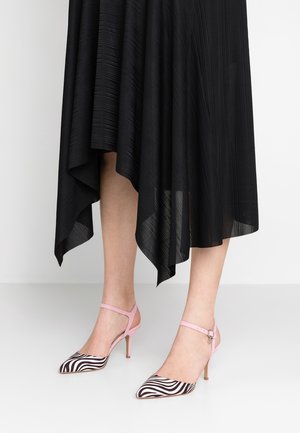 Voeten met zebra gestreepte puntige hakken met roze enkelbandjes, gecombineerd met een zwarte asymmetrische geplooide rok.