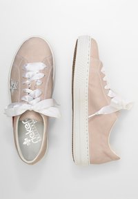 Jasnoróżowe trampki na płótnie z srebrną gwiazdą, białymi satynowymi sznurowadłami oraz teksturowaną gumową podeszwą z beżowym akcentem.