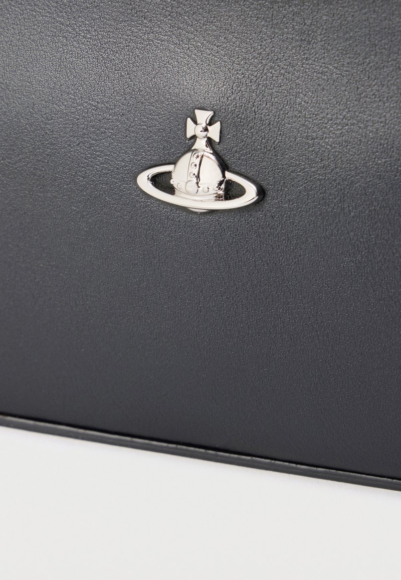 Matériau texturé noir présentant un emblème métallique argenté en forme de couronne dans un anneau, ajoutant un accent distinctif au design.