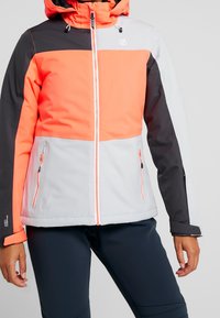 Farbenblockierte Skijacke mit orangen, grauen und schwarzen Panels. Der Stoff ist glatt und verfügt über Reißverschlusstaschen sowie eine Kordelzugkapuze.