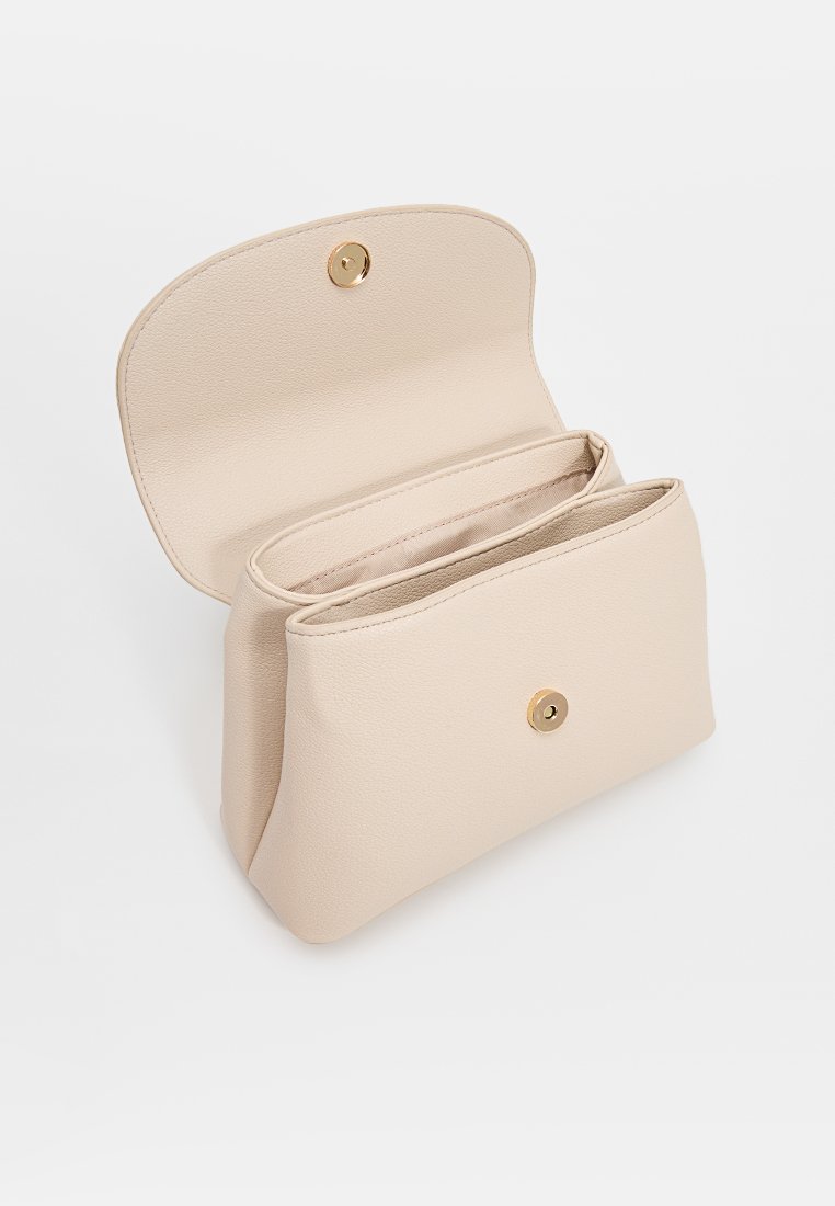 Beige faux leren pouch met een ronde vorm, gouden drukknoopsluiting en twee vakken binnenin. Gladde textuur, minimalistisch ontwerp.