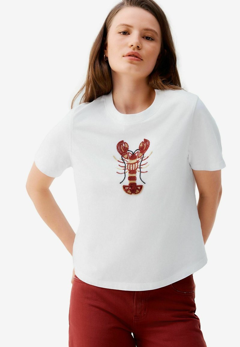 Tricou alb cu maneci scurte, prezentând un broderie detaliată de homar în nuanțe de roșu, maroniu și negru. Tricoul are o guler rotund și o croială lejeră.