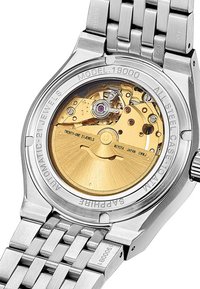 Reloj automático de acero inoxidable con un fondo de caja transparente que revela un movimiento dorado y un acento púrpura. Cristal de zafiro.