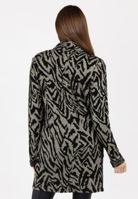 Długi kardigan z czarno-szarym, abstrakcyjnym nadrukiem zwierzęcym, wykonany z miękkiego, dzianinowego materiału, o luźnym kroju i otwartym przodzie.