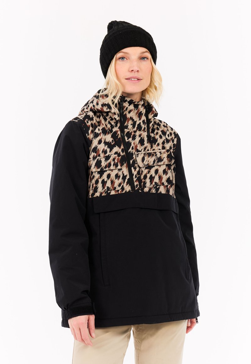 Schwarze Pulloverjacke mit einem Leopardenmuster auf der Vorderseite, einem Reißverschluss-Brusttasche und verstellbare Kapuze. Getragen mit einer schwarzen Strickmütze.
