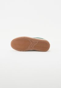 Såle med strukturert gummi i tan-farge, med PUMA-logo og bølgete mønster. Rent design med lette kurver og kanter.