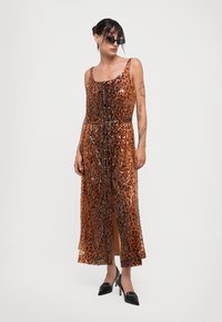 Rochie cu aplicații de paiete în bronz, cu o siluetă fluidă, cu lungime până la genunchi și o fanta centrală. Bretele ajustabile și talie ajustată.