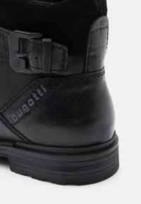 Botte de cheville en cuir noir avec un logo "bugatti" en relief et une sangle de boucle noire mate sur un fond blanc.