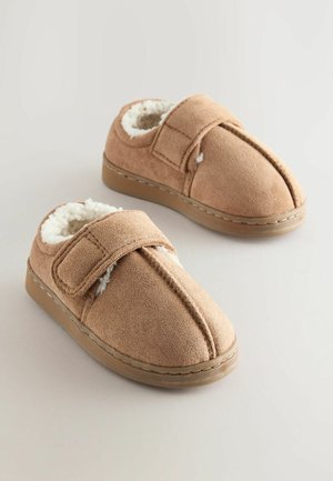 Tan slip-on slippers med blød, kunstig pelsforing, der har en velcrorem og et rundt tådesign. Flad sål med stitched kanter.