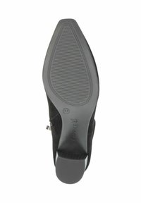 Suela de zapato de ante negro con forma puntiaguda, patrón de agarre de goma y un pequeño tacón. La marca Caprice es visible cerca del tacón. Tamaño 37.