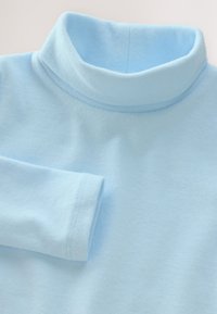 Světle modrý rolák z měkké látky, s rolovaným límcem a dlouhými rukávy. Hladká struktura s pečlivými švy.