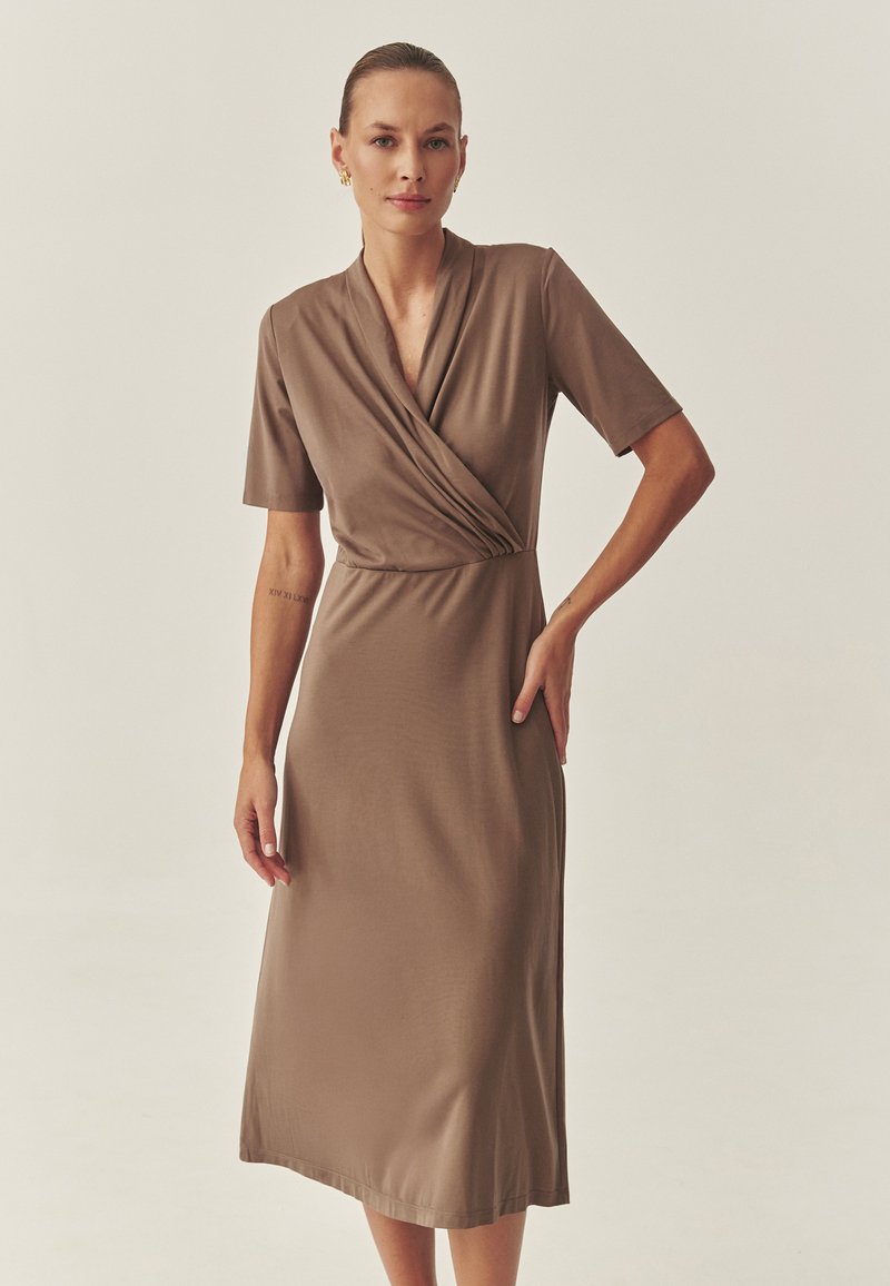 Braunes, knielanges Kleid mit Wickeldesign, kurzen Ärmeln und glatter Textur. Merkmale sind ein tiefes V-Ausschnitt und eine taillierte Passform.