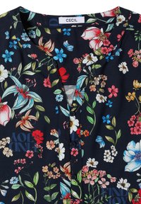Blouse foncée avec motif floral multicolore, col rond, boutonnière devant et étiquette de marque "CECIL" à l’intérieur du col.