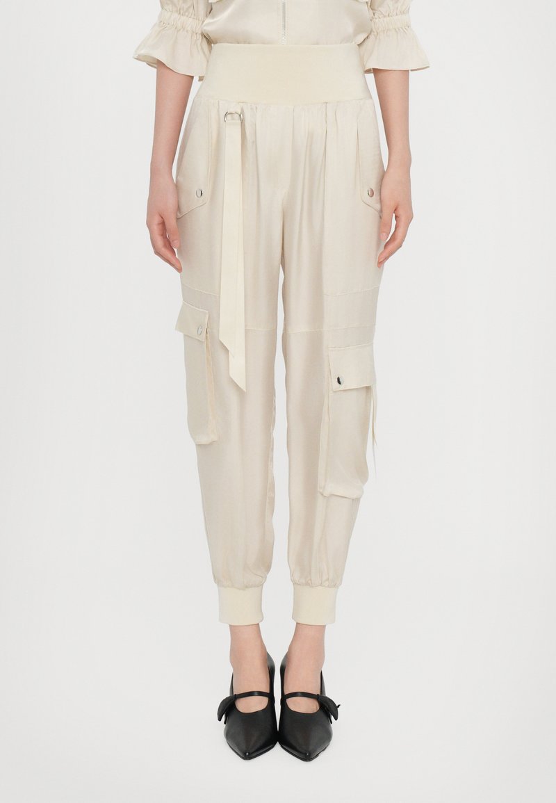 Beige Cargo-Hosen mit einem breiten Bund und verstellbarem Bindegürtel. Mit Seitentaschen, elastischen Bündchen und einem glatten, leichten Stoff.
