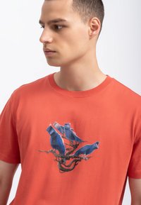 Rode katoenen T-shirt met een grafische afbeelding van blauwe vogels op een bruine tak, ronde halslijn en korte mouwen. Gladde textuur, casual ontwerp.