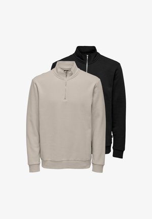 Twee lange mouwen quarter-zip sweaters, één beige aan de voorkant en één zwart aan de achterkant, beide met rechtopstaande kraag en geribde manchetten en zomen.