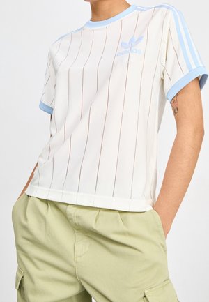 Biała koszulka z pionowymi paskami i jasnoniebieskimi akcentami, z okrągłym dekoltem i krótkimi rękawami. Logo Adidas w jasnym niebieskim kolorze na klatce piersiowej.