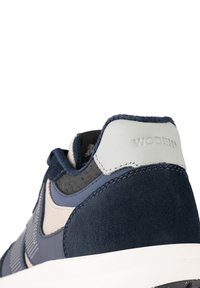 Navy and light gray athletic shoe with suede and mesh upper, featuring a textured design and embossed logo at the heel. White sole.