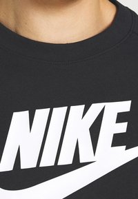 Svart bomull T-shirt med en stor vit Nike-logotyp över framsidan. Kragen är rund och ribbad, med en mjuk yta.