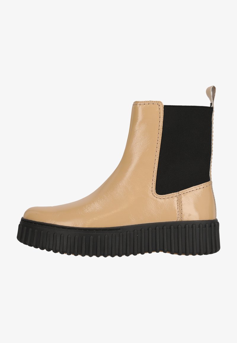 Bottine en cuir verni beige avec panneau latéral élastique noir et semelle épaisse en caoutchouc noir présentant des rainures verticales.