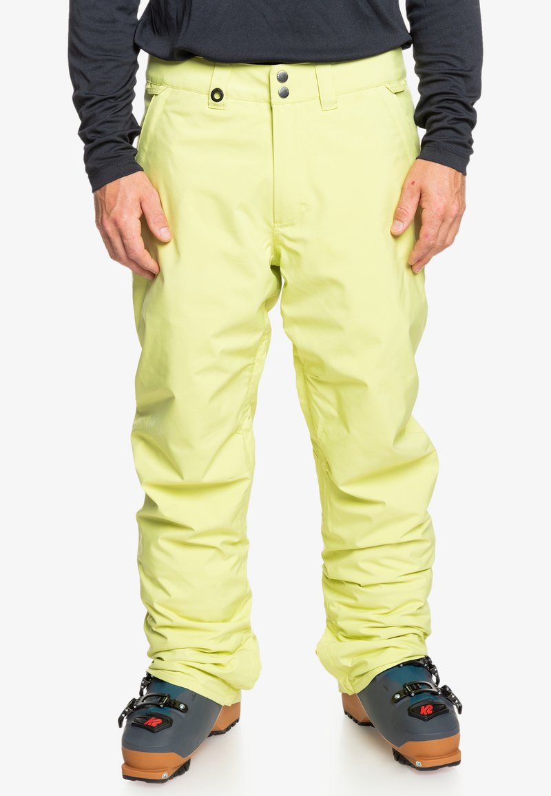 Vaaleankeltaiset eristyslumihousut, jotka on valmistettu vettä hylkivästä materiaalista. Housuissa on suora leikkaus, kaksinkertaiset napit ja joustavat hihnat.