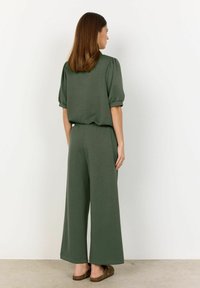Pohodlný dvoudílný outfit v jedné olivově zelené barvě. Top má krátké puff rukávy; kalhoty s širokými nohavicemi mají elastický pás. Přirozená textura látky.