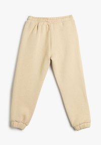 Pantalones de chándal beige hechos de una tela suave, con una cintura elástica y puños gather en los tobillos para un ajuste relajado.