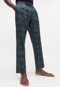 Groene en marineblauwe geruite broek met een ontspannen pasvorm, elastische tailleband en trekkoord. Zacht materiaal met een gladde textuur.