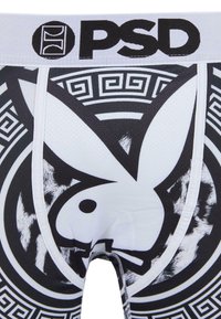 Valkoiset ja mustat graafiset bokserit, joissa on suuri pupulogo, geometriset mustat yksityiskohdat ja brändätty elastinen vyötärö.