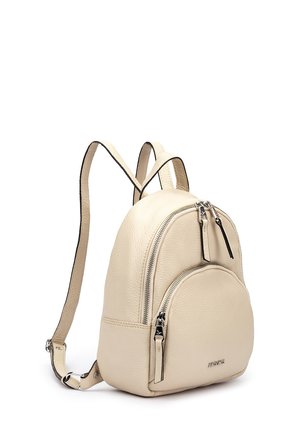 Mochila pequeña de cuero beige con dos compartimentos con cremallera y correas de hombro ajustables sobre un fondo blanco.