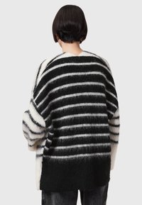 Oversized zwart-wit gestreepte trui, gemaakt van zacht, fuzzy materiaal met verschillende stripebreedtes, met verlaagde schouders en een ronde zoom.