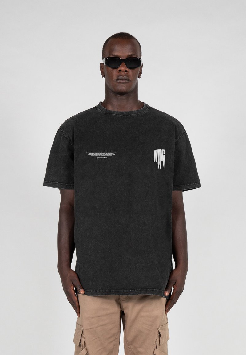 Sort denim t-shirt med rund halsudskæring, korte ærmer og hvide trykte detaljer på brystet og siden. Båret med khaki cargo shorts.