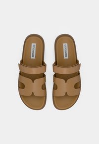 Braune Rutschen Sandalen mit zwei breiten Riemen, ausgeschnittenem Design im Obermaterial und einer strukturierten Sohle. Branding auf der Innensohle sichtbar.